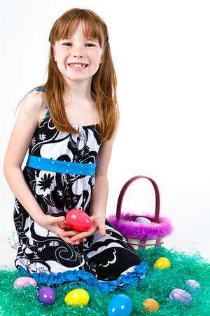 Young girl sitting in grass with an Easter eggの写真素材