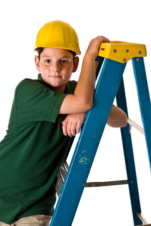 A young boy wearing a hard hat and leaning on a ladder. Sweat beads can be seen on his face from the hard construction work he has been doing. Isolated on a white background.の写真素材