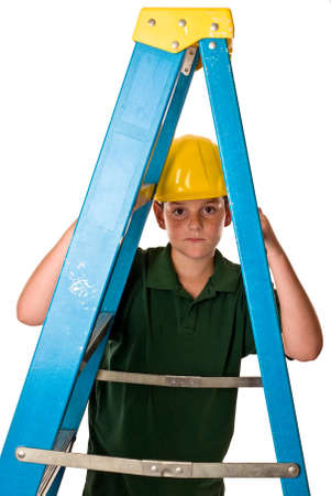 A young boy wearing a hard hat and looking through a ladder. Sweat beads can be seen on his face from the hard construction work he has been doing. Isolated on a white background.の写真素材