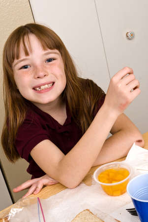 Young school girl eating lunchの写真素材