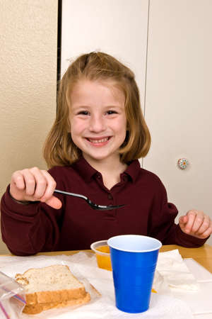 Young school girl eating lunchの写真素材