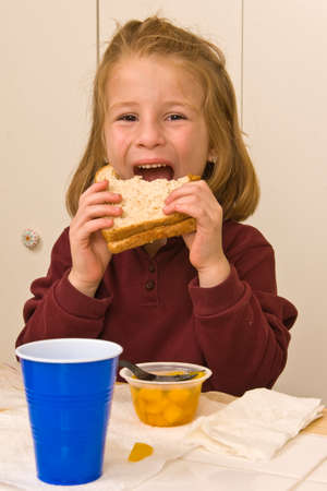 Young school girl eating a healthy lunchの写真素材