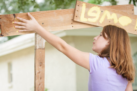 A young girl painting a hand print on a lemonade stand signの写真素材