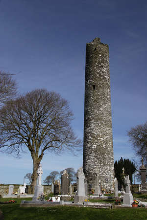 Monastic round tower in grave yard, ireland and blue skyの写真素材