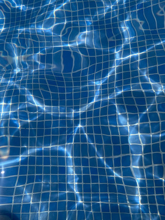 Blue rippled water in the swimming pool with sun reflection