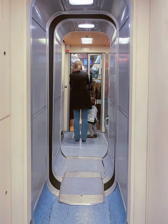 Woman with child, walking inside moving train with long corridor, doors