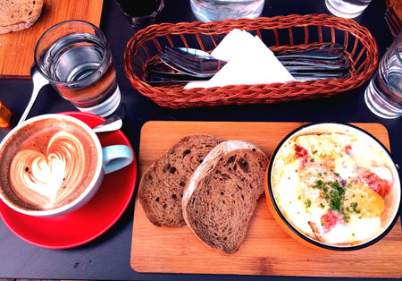Weekend brunch of mocha and baked eggs with beans, chorizo sausages and bacon