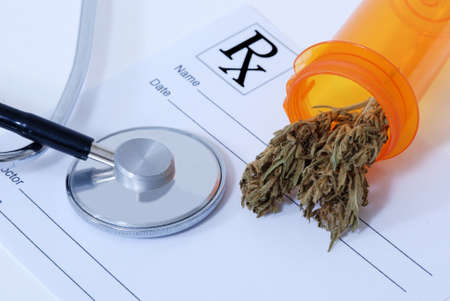 Cannabis bud sitting on a prescription pad, near a stethoscopeの写真素材