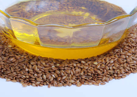 Flaxseed oil in bowl and whole flax seeds.  Isolated on white.の写真素材