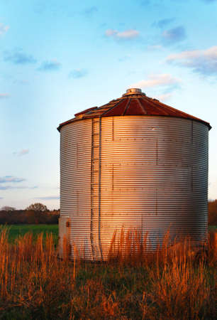 grain silo with corrugated metal.  Against a blue sky and brown grass.の写真素材
