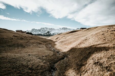 A field in the mountains in northern italy with a small stream in the middle of the picture.の写真素材