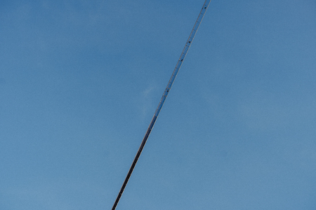 A suspension bridge directly from below with a celan blue sky in the backgroundの写真素材