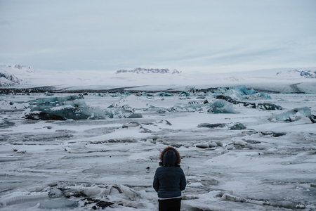 A person standing in a glacier lagoon at Iceland, looking at the landscapeの写真素材