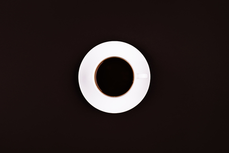 Coffee in a mug with a plate underneath on dark backgroundの写真素材