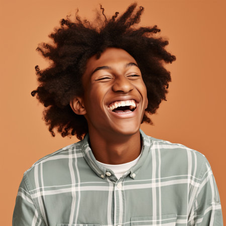 A playful, African American Generation Z teen with curly hair winks, displaying his perfect white teeth in a close-up portrait on a beige background.の素材