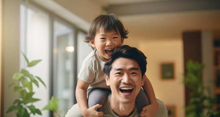 Ecstatic Asian father having a blast with his young son in the living space, bonding and enjoying quality time at their residence.の素材