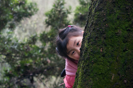little girl behind the tree trunk