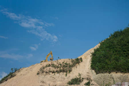 Yellow Excavator at Work on a mountain, Vegetation destroy leads to erosion and environmental destruction.の写真素材
