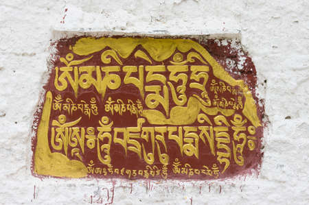 The Sanskrit mantra 'Om mani padme hum' inscribed and painted on a mani stone embedded in a wall of the Potala Palace in Lhasa, Tibet, China.のeditorial素材