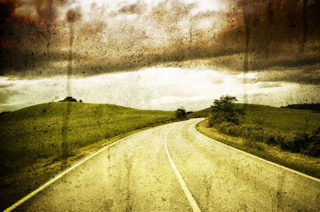 Road between fields under a cloudly skyの写真素材