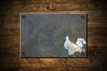 An old grunge metal plate on a wooden backgroundの写真素材