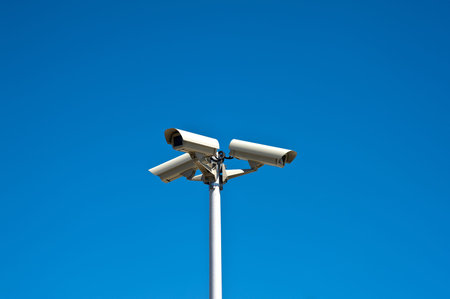 Three security cameras isolated on a blue sky