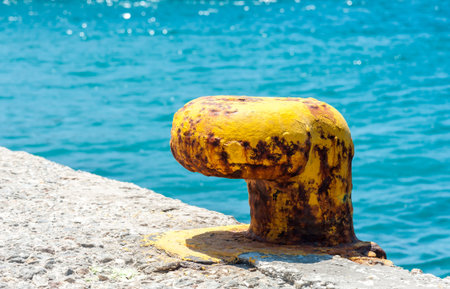 Old grunge yellow bollard in Naxos - Greece