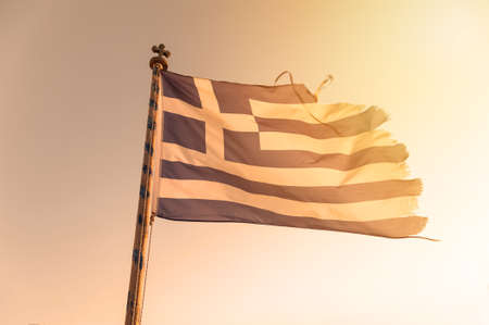 Damaged greek flag in the sunsetの写真素材