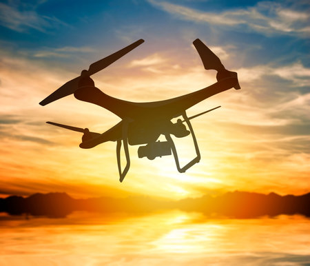 Silhouette of a drone with digital camera flying in a sunset sky: 3D rendering