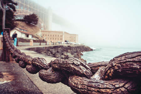 Golden Gate Bridge in the fog as seen from behind a railing chain at the Presidioの写真素材