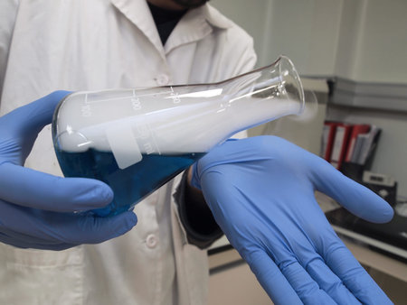Close up of a glove hands showing a flask with a blue liquid and dry ice inside. Sublimation, steam....