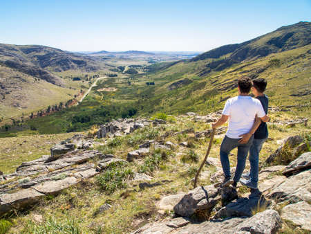 Young homosexual couple looking at the view in Cerro BahÃ­a Blanca, Sierra de la Ventana, Buenos Aires, Argentina.の写真素材