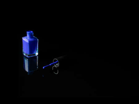 Blue nail polish bottle opened with the brush out on black background with refection. Horizontal. Beauty and cosmetic concept.の写真素材