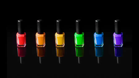 LGBT flag colors nail polish bottles on black background with refection. Beauty and cosmetic concept.の写真素材