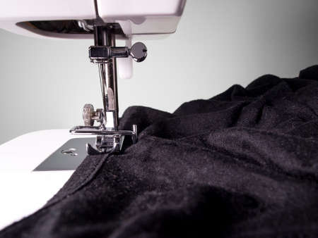 Sewing machine detail with a black fabric on a white wall background. Copy space, black and white. Craft concept.の写真素材