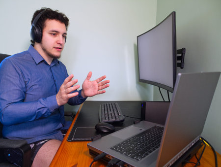 Young caucasian programer man in underwear with headphones talking with his coworkers by a...