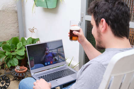 Man talking and having a beer with his father on a videocall. Distance communication concept.の写真素材