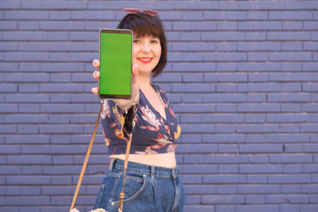 Young caucasian woman showing her smartphone with chroma key to the camera. Coronavirus prevention...