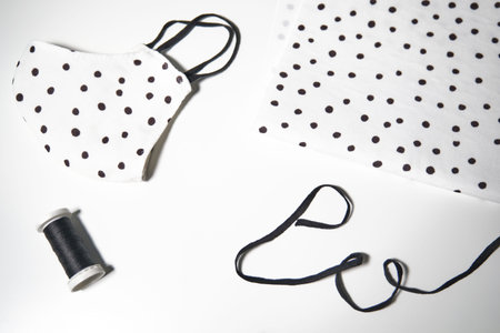 Top view of black and white polka dots fabric with filter, thread, rubber band and anti-virus fabric...