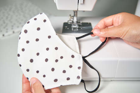 Woman hands sewing a face medical mask at a sewing machine. Do it yourself, zero waste and coronavirus concepts.の写真素材