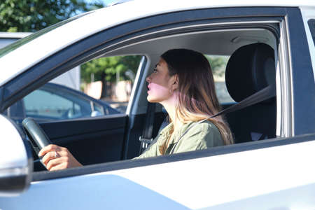 Young woman starting the car and checking the rear view mirror. Drive concept.の写真素材