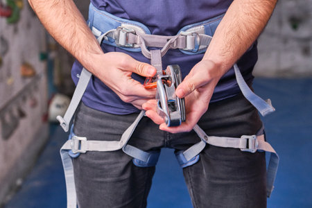 Close-up of climber with climbing equipment, tying snap hook on safety climbing harness, preparing for climbing. Unrecognizable person detail.の写真素材