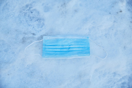 Used medical protective face mask on the snow.  pandemic.の写真素材