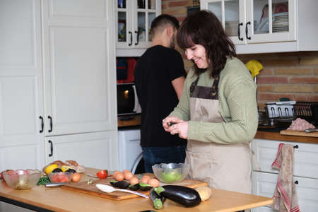 A couple of friends smiling and cooking vegetarian food. Mediterranean, healthy and vegetarian diet.の写真素材