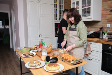 A couple of friends smiling and cooking. Cooking mediterranean and healthy food.の写真素材