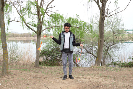 Young punk man juggling cariocas in a park. Rock and roll lifestyle.
