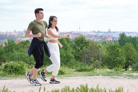 Young sporty couple running and checking the smartwatch outdoors. Two jogger friends.