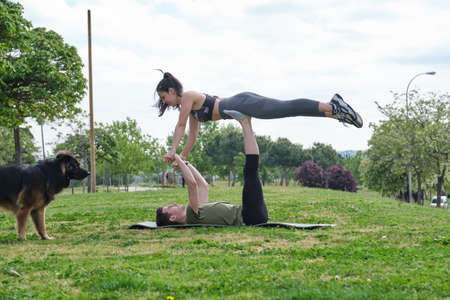 Young sporty couple practicing acro-yoga fly pose on the grass. Fitness outdoor.の写真素材