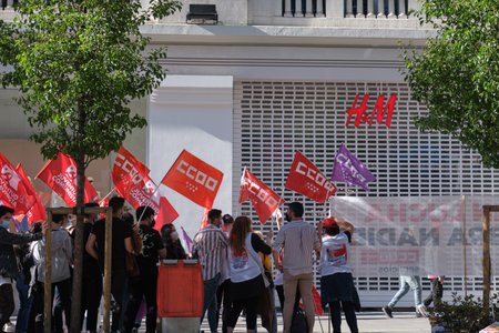 Madrid, Spain. May 14, 2021: Group of people protesting with CCOO, UGT and Juventud comunista flag in front of a H&M shop because of an ERE for 1100 workers.のeditorial素材