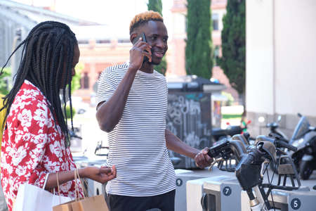 Young african tourists renting a bike at a bicycle rental service machine. City life concept.の写真素材